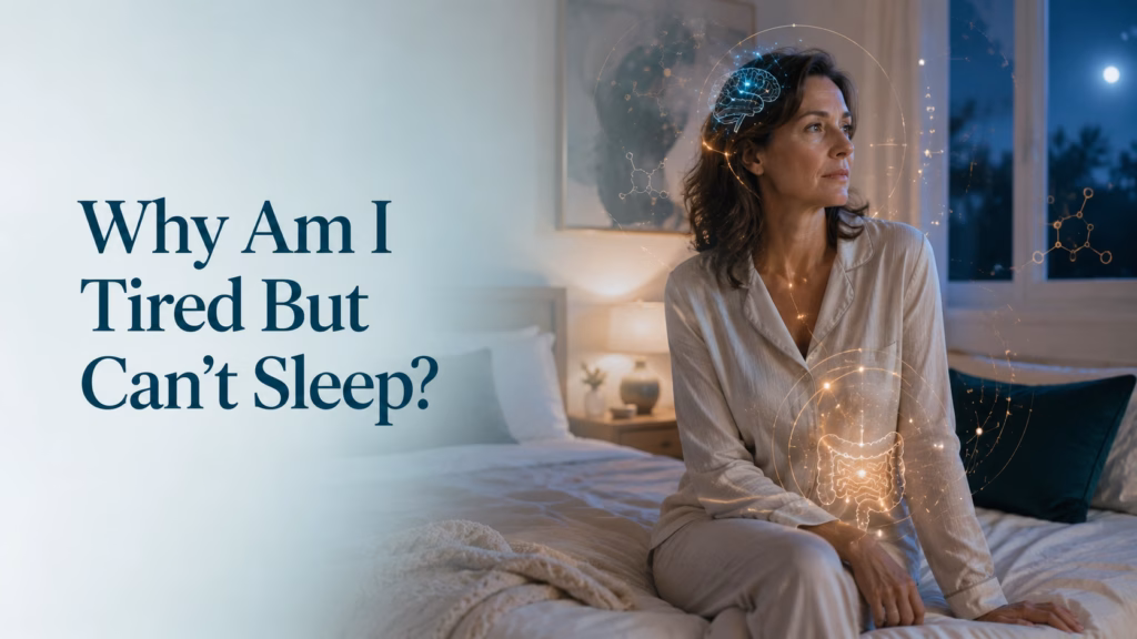 Why am I tired but can't sleep? Luxury functional medicine blog header featuring a thoughtful midlife woman sitting awake in a modern bedroom at night, illustrating the connection between hormones, gut health, stress, and insomnia.